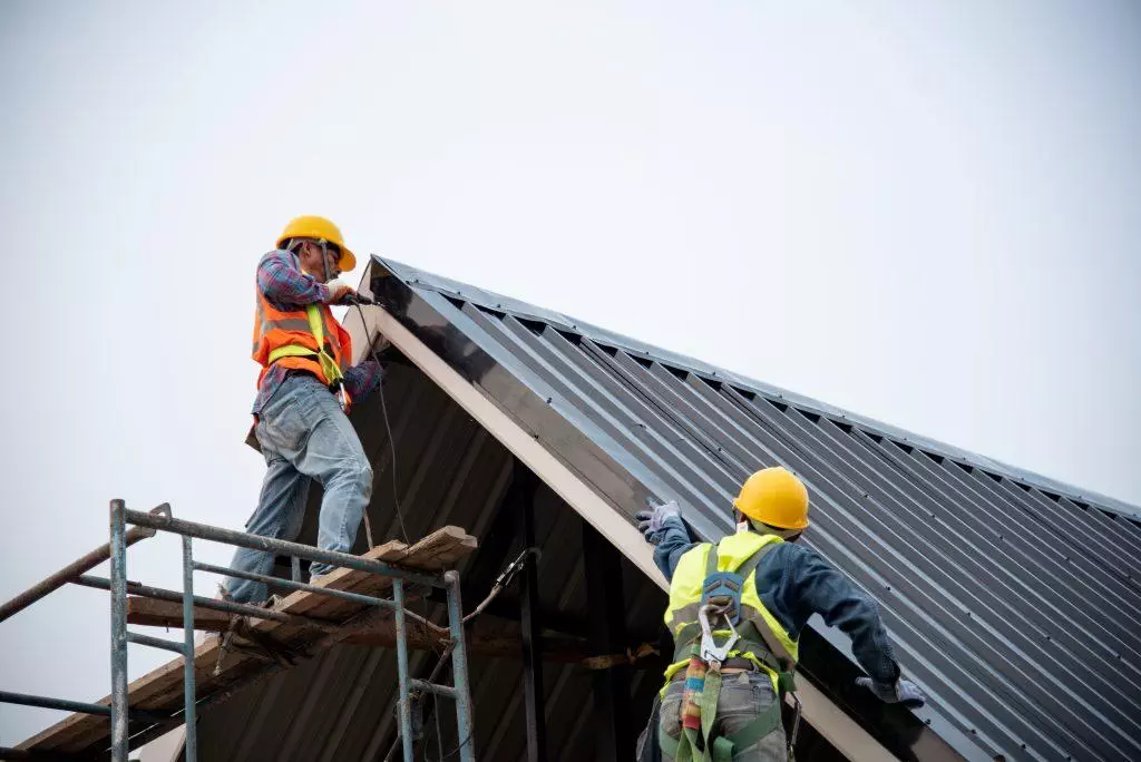 Technician is Work Roof Repair Construction engineer wear safety uniform inspection metal roofing work for roof.